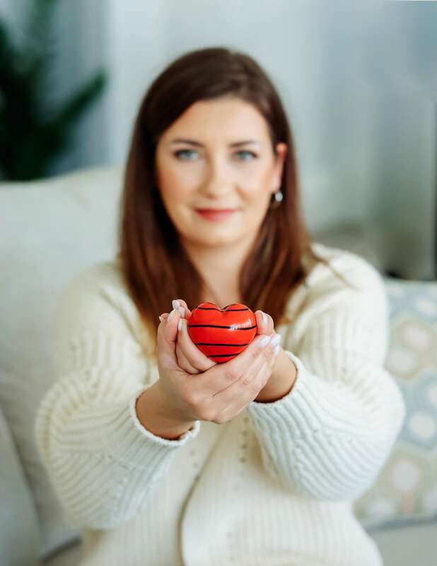 Hands holding a red heart, symbolizing care and support